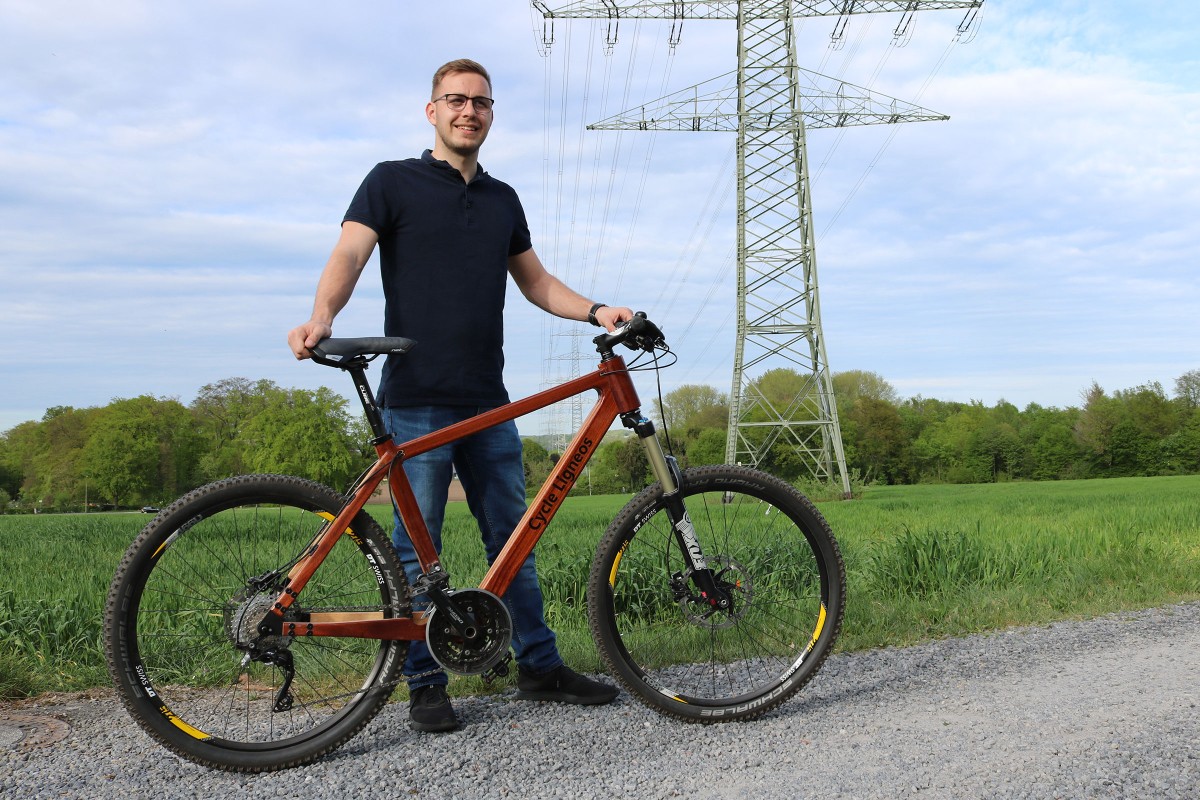 Ingenieur Carsten Levermann steht hinter seinem selbst gebauten Fahrrad mit einem Holzrahmen 