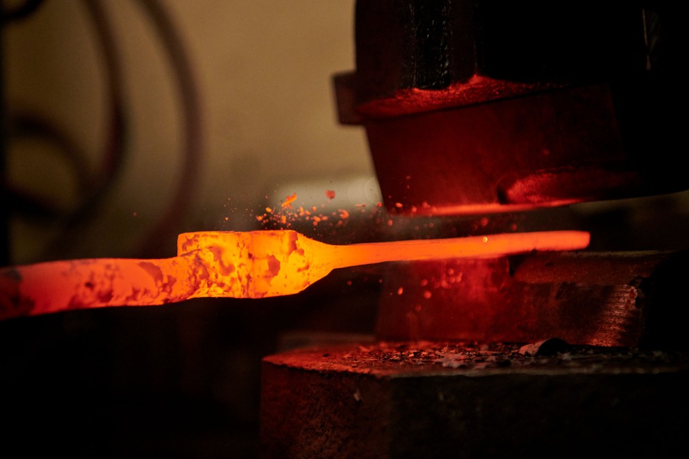 
				Glühender Stahl wird vom Federhammer flach gepresst.

			