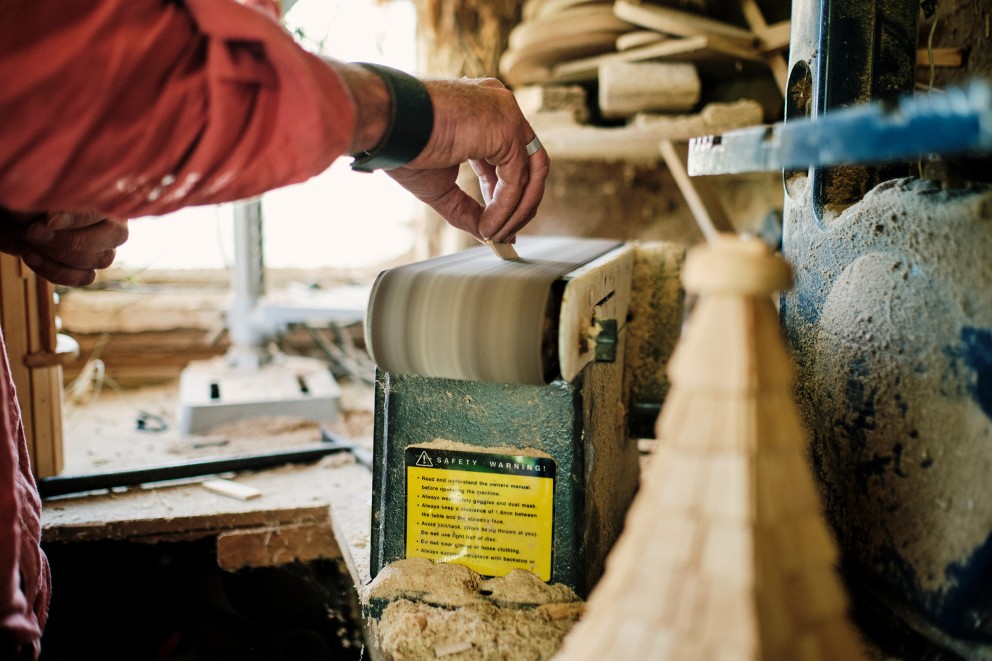 
				Der erste Schliff: Jedes Stück wird zunächst mit der Schleifmaschine in Form gebracht, bevor es an das Holzgebäude geklebt oder genagelt wird.

			